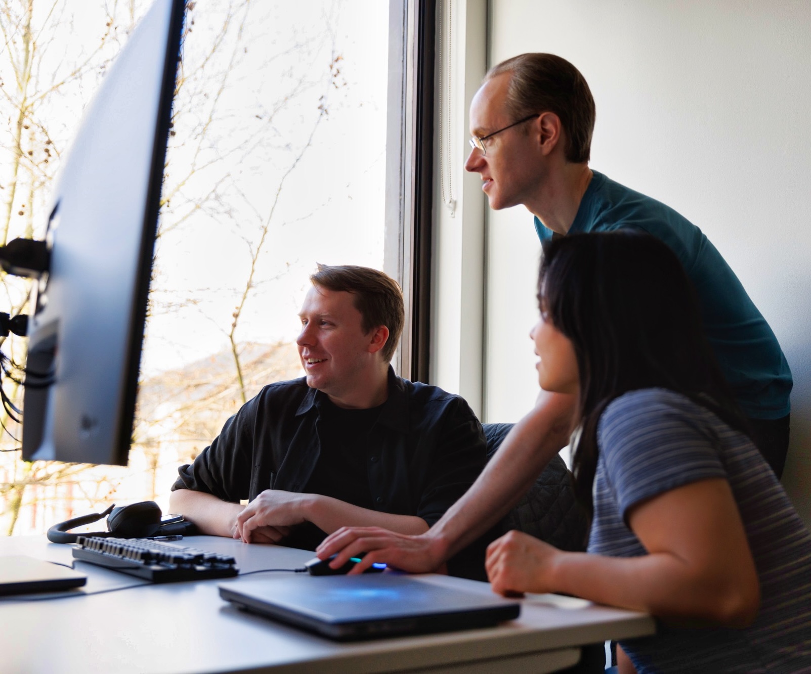 A team of colleagues collaborating in a meeting while looking at the computer screen.